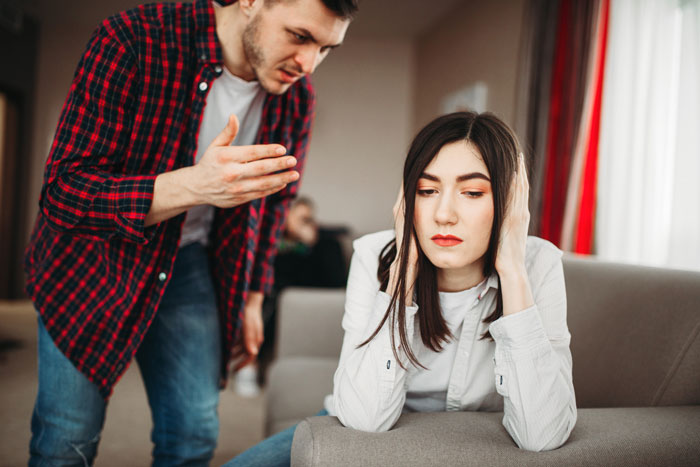 A toxic guy arguing with his GF, who covers her ears, illustrating the effects of his jealousy and rules.