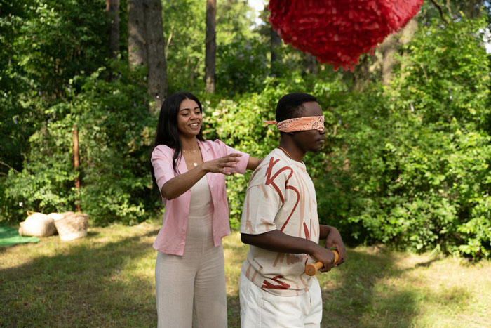 Couple playing boyfriend pinata game outdoors with blindfold and bat Couple playing boyfriend pinata game outdoors with blindfold and bat