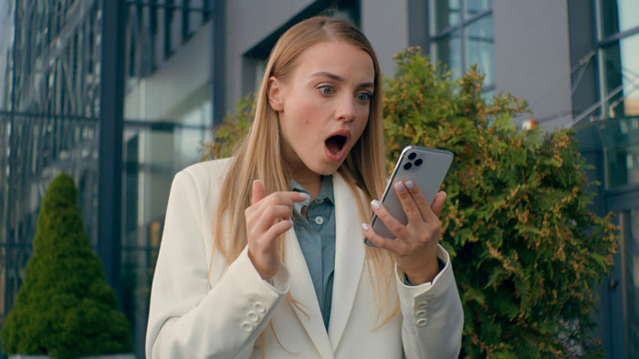Surprised woman looking at smartphone, shocked by relationship piñata news Surprised woman looking at smartphone, shocked by relationship piñata news