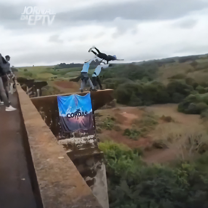 Person jumping off bridge during rope jumper activity with others nearby Person jumping off bridge during rope jumper activity with others nearby