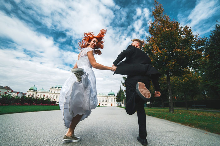 Bridal couple running away joyfully to escape falling apart wedding day