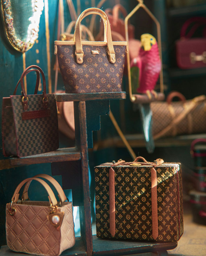 Designer handbags and luggage displayed on wooden shelves