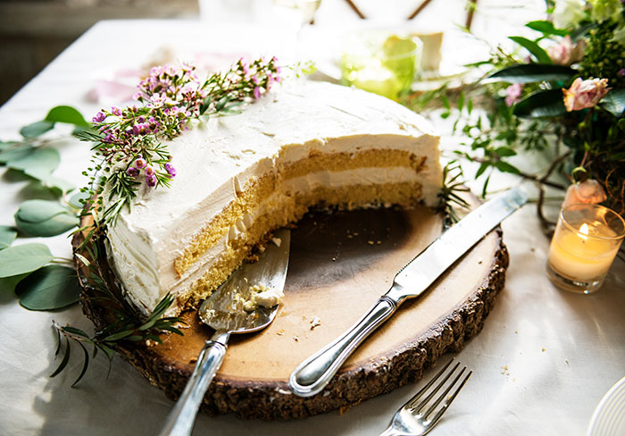 Wedding cake partially eaten with flowers and cutting utensils Wedding cake partially eaten with flowers and cutting utensils