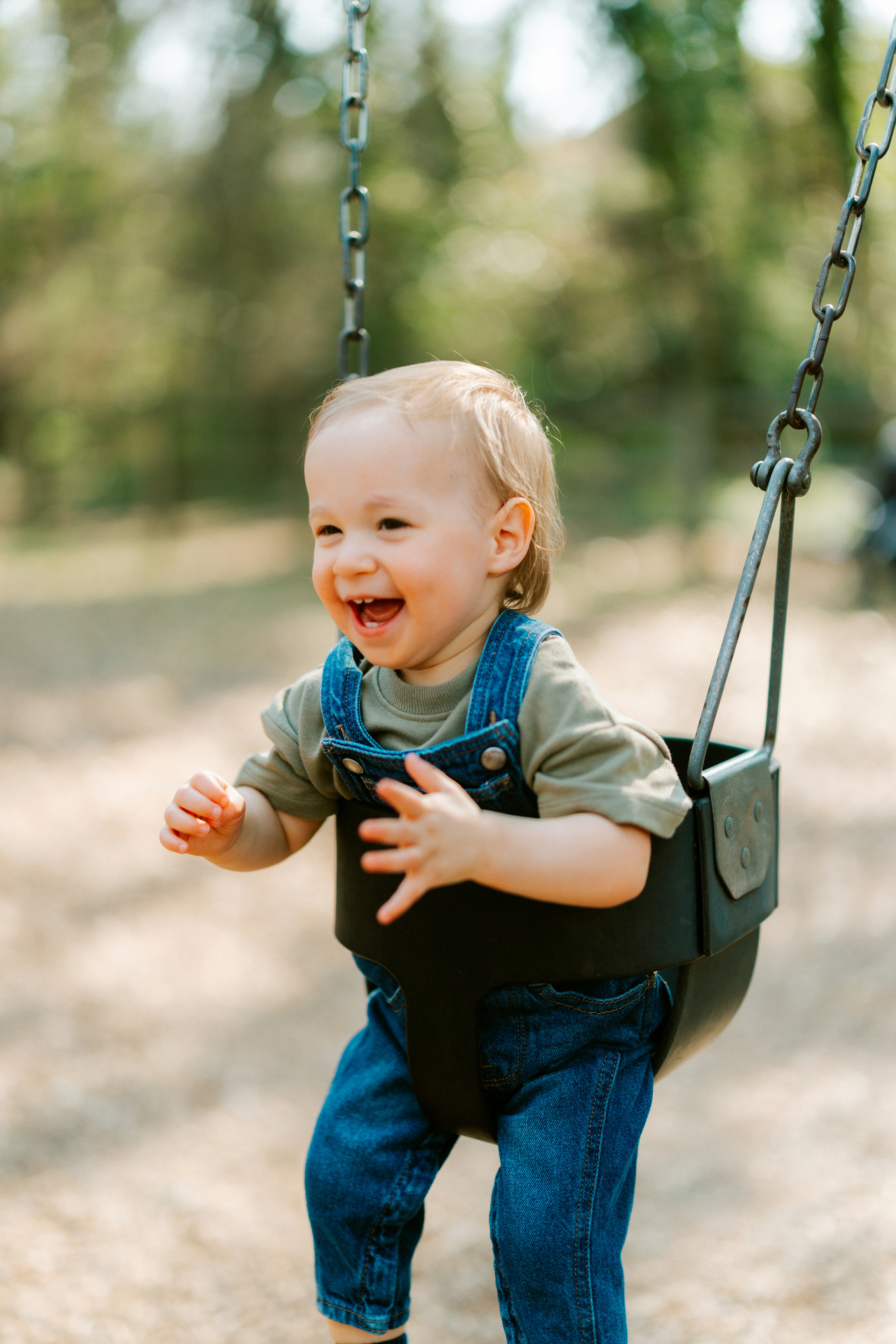 Happy toddler boy playing on a swing outdoors