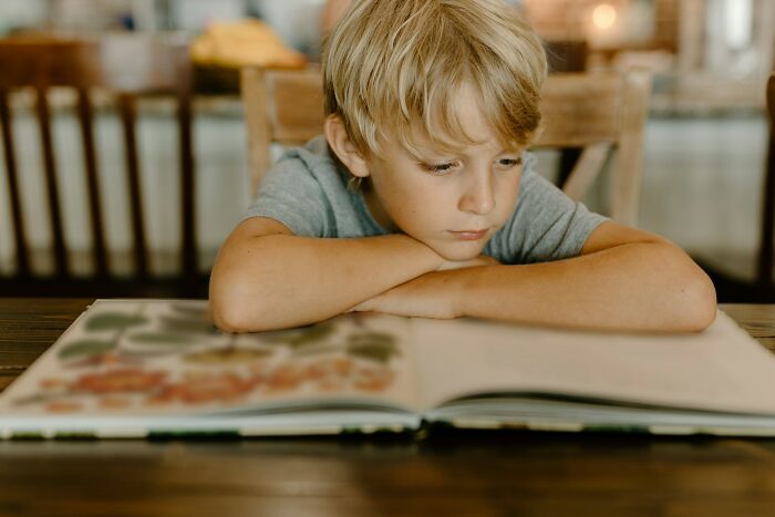 Boy looking thoughtfully at book highlighting Gen Alpha literacy issues