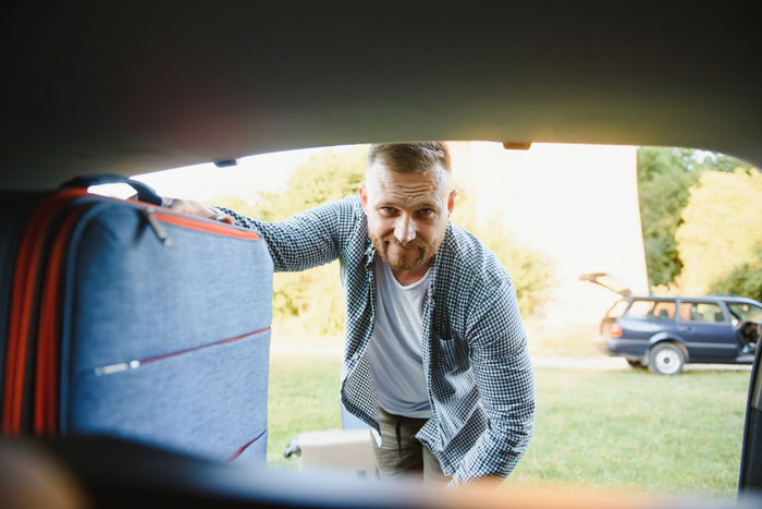 Man loading luggage for a beach trip, possibly affected by the bully incident. Man loading luggage for a beach trip, possibly affected by the bully incident.