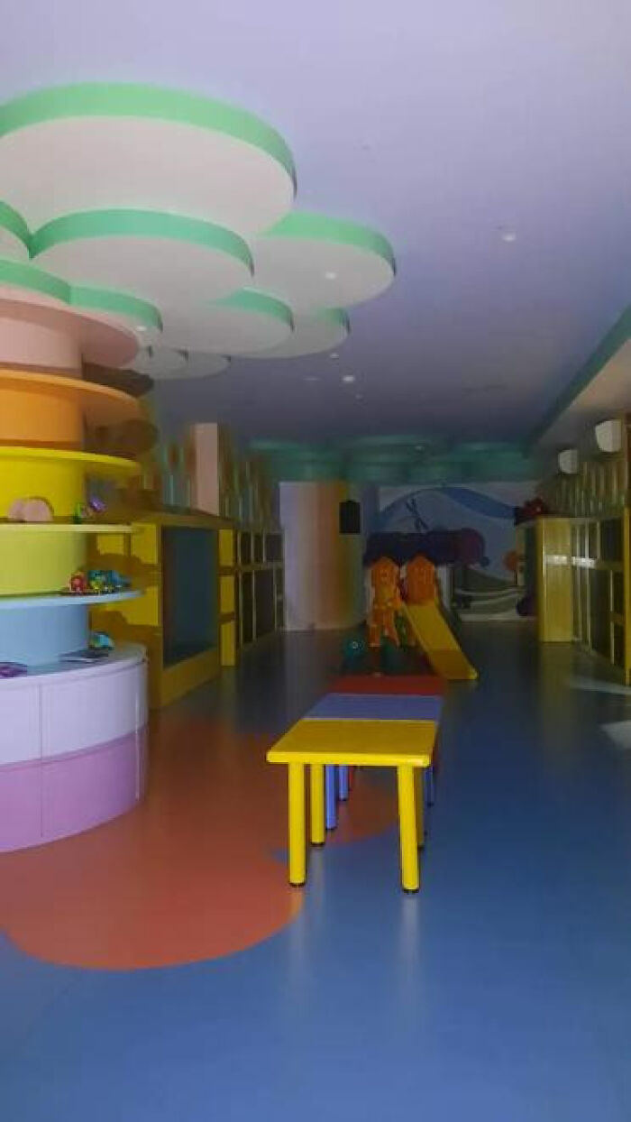 An empty, brightly colored children's play area with slides and tables, a haunting liminal space.