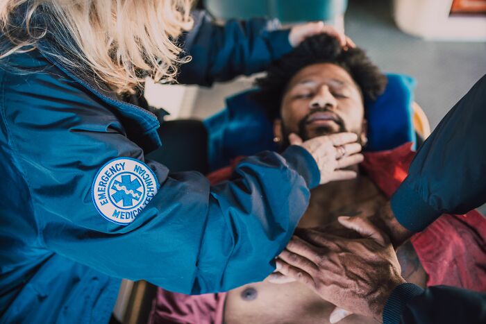 Emergency medical technician assessing patient on stretcher