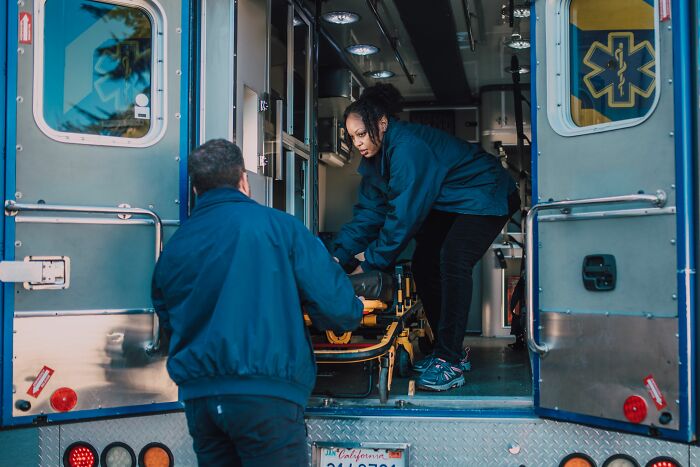 Paramedics preparing a stretcher inside an ambulance