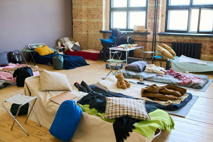 Temporary shelter with cots, pillows, and personal items arranged in a room