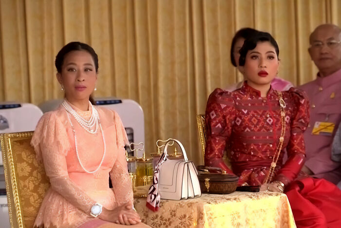 Two women in traditional Thai dresses at ceremonial event Two women in traditional Thai dresses at ceremonial event