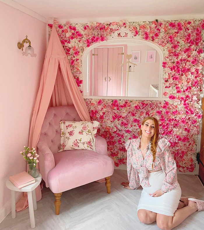 A pregnant woman smiles in a room with a pink floral wall and matching decor, exemplifying questionable renovations that devalued homes. A pregnant woman smiles in a room with a pink floral wall and matching decor, exemplifying questionable renovations that devalued homes.