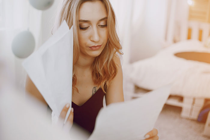 A woman looking at documents, devastated at not being made a bridesmaid, realizing her friendship has run its course.