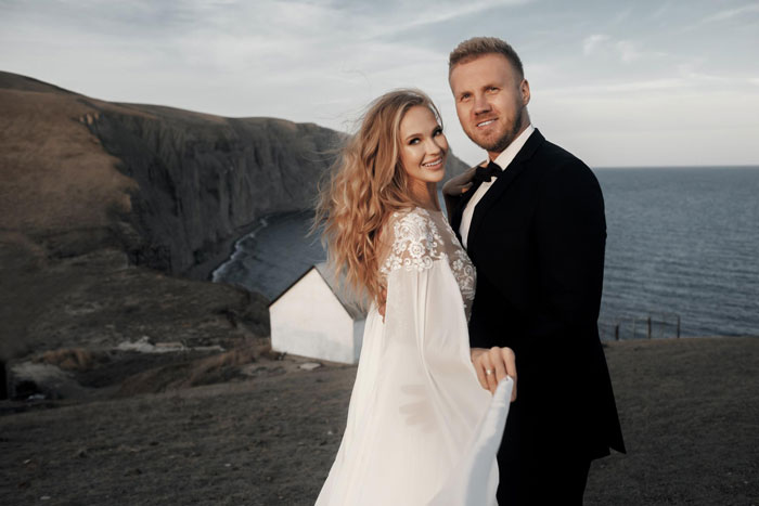 Happy couple smiles in wedding attire at their destination wedding overlooking the ocean and cliffs. Happy couple smiles in wedding attire at their destination wedding overlooking the ocean and cliffs.