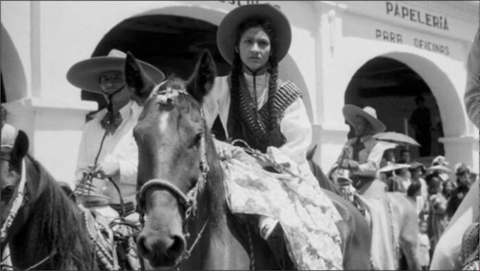 A woman on horseback, wearing a sombrero and bandolier, in a historical photo that feels almost impossible to explain.