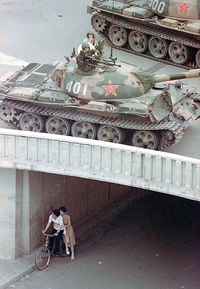 Historical photos capturing two tanks on a street above a couple on a bicycle, an impossible explanation.