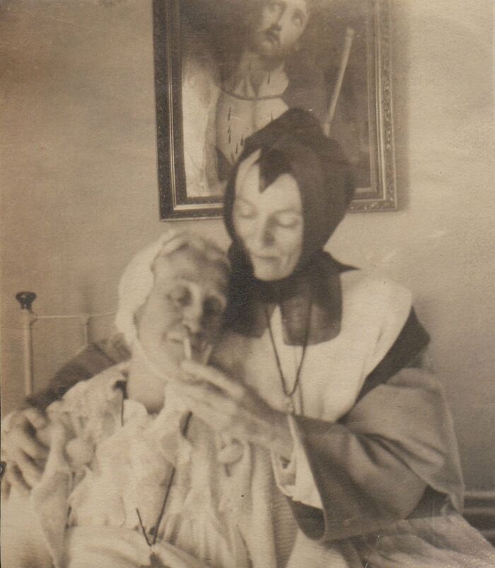 A nurse tends to a patient in bed in a historical photo that is hard to explain.