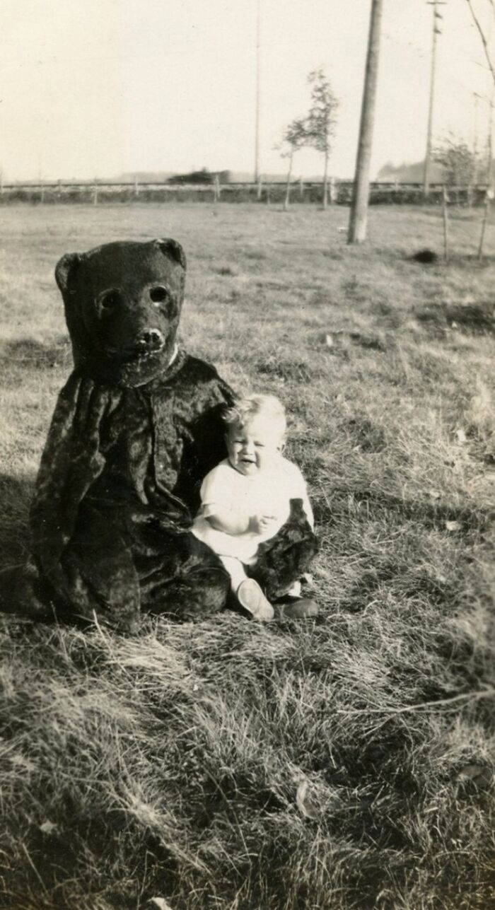 A baby cries beside a person in a scary bear costume, one of many historical photos.