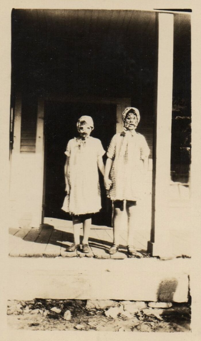 Historical photos of two young girls in unsettling masks, holding hands on a porch, an impossible explanation.
