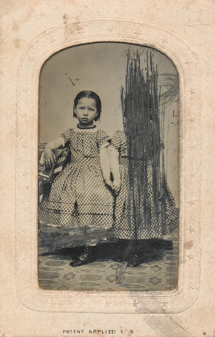 A haunting historical photo of a young girl with an unexplainable blurred figure beside her, adding to the mystery.