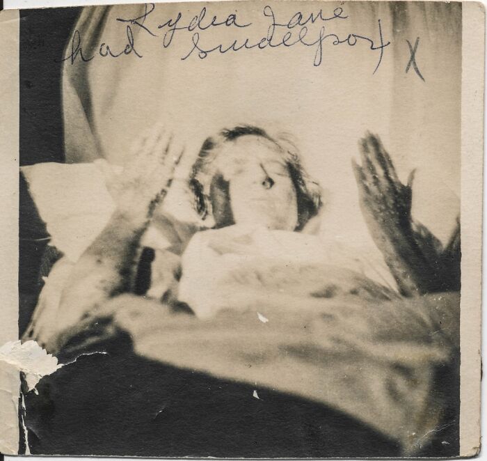 An eerie historical photo of a person with hands raised, featuring old handwriting above, creating an unexplainable scene.