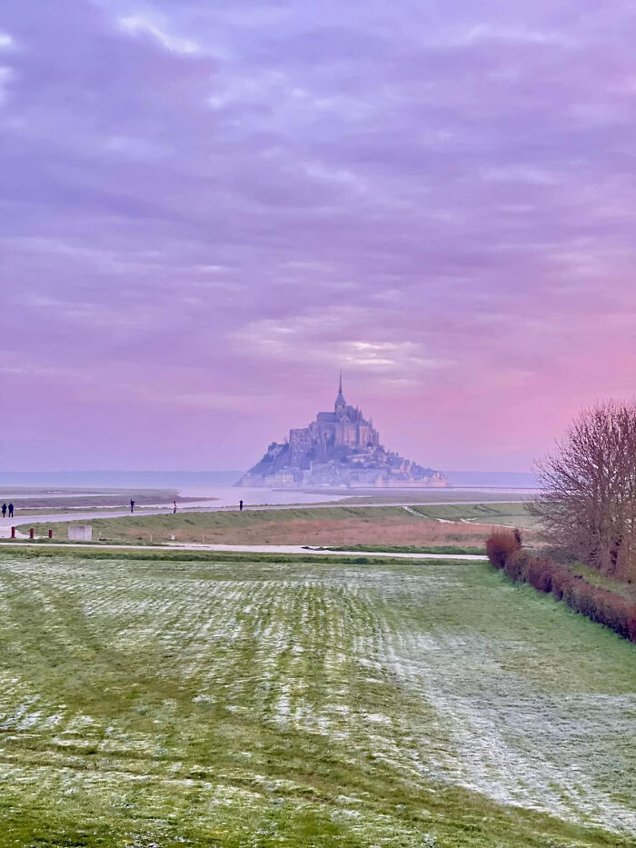 Aesthetic landscape with Mont Saint Michel in the distance under a purple and pink cloudy sky