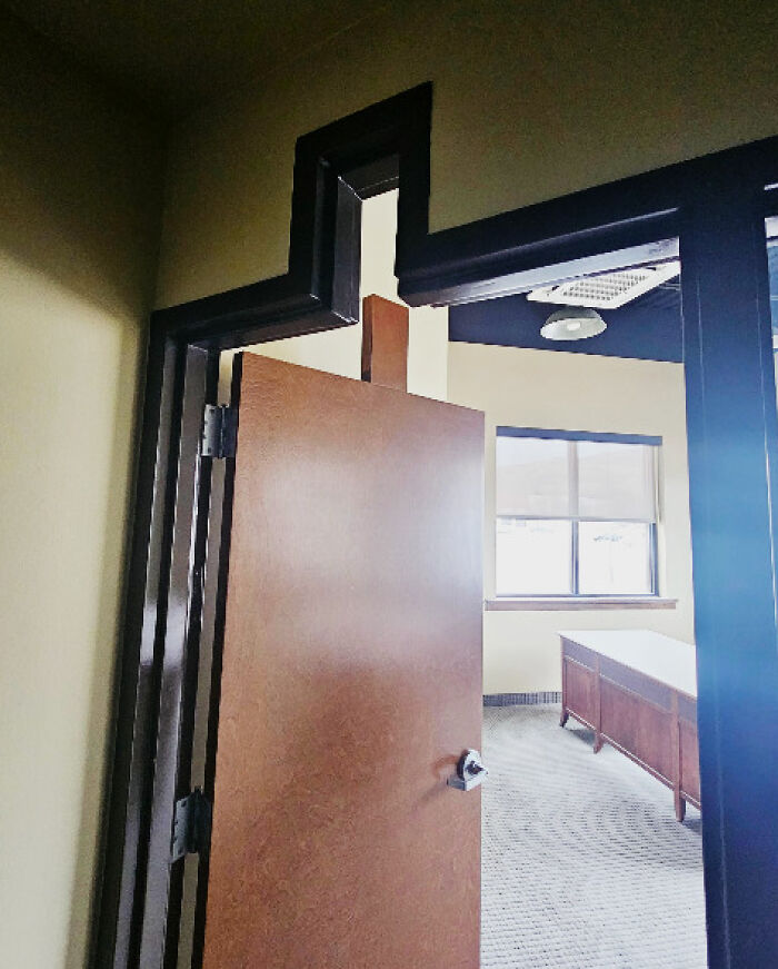 An irregularly shaped doorframe and a wooden door, highlighting architecture and design fails.