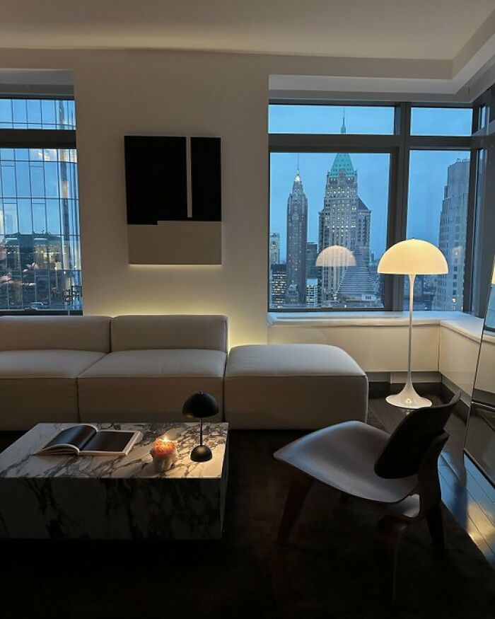 Sleek modern living room with white sofa, marble coffee table, and cityscape view through large windows