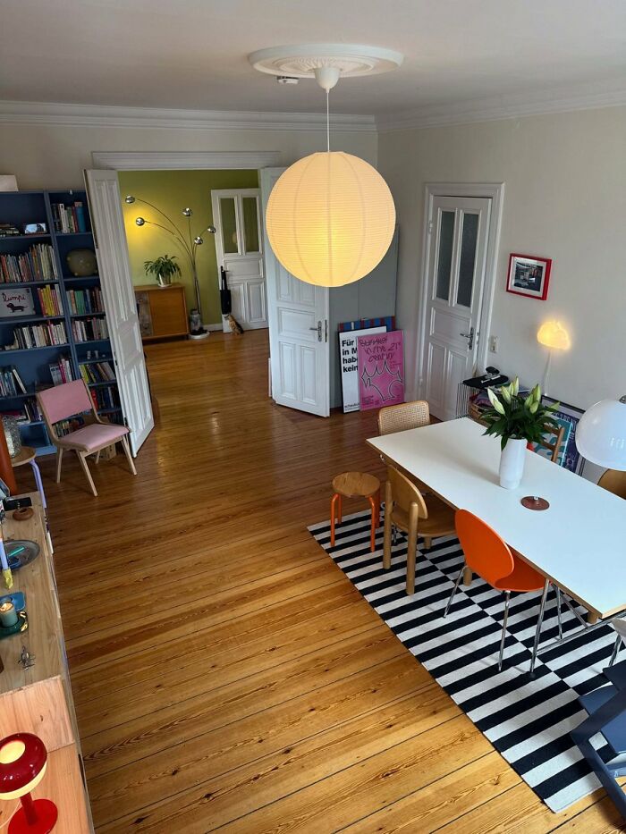 Bright dining room with wooden floor, striped rug, and a round hanging paper lantern