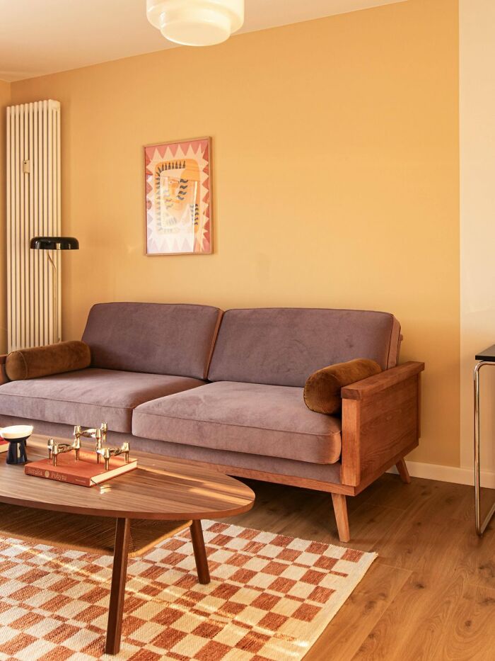 Minimalist living room with wooden sofa and warm wall color highlighting cool interior design
