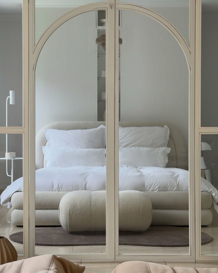 Modern bedroom reflected in arched mirror in cool interior design