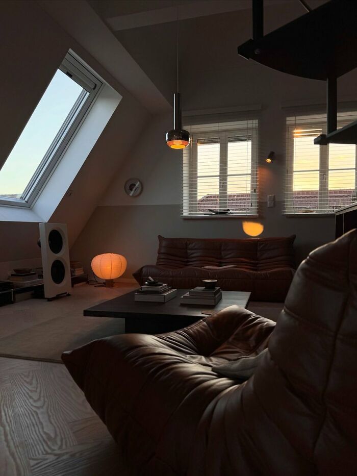 Dimly lit attic living room with leather furniture in interior design