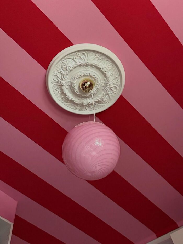 Pink and red striped ceiling with decorative light fixture interior design inspiration