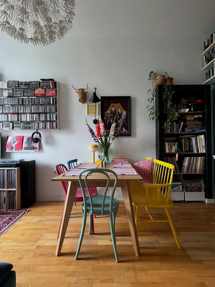 Dining room with mixed colorful chairs and wooden table under white wall art interior design ideas