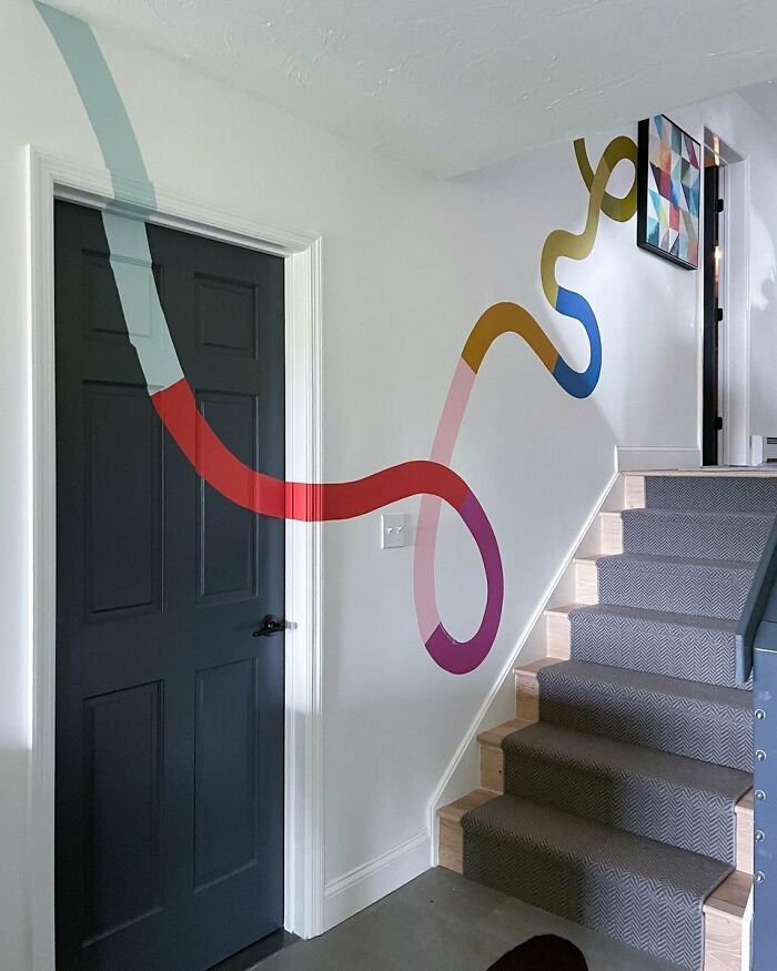 Colorful wall art design wrapping around staircase and black door