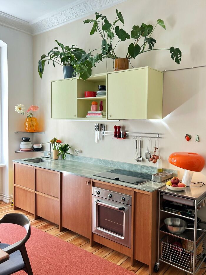 Modern kitchen interior design with green upper cabinets and wooden lower cabinets
