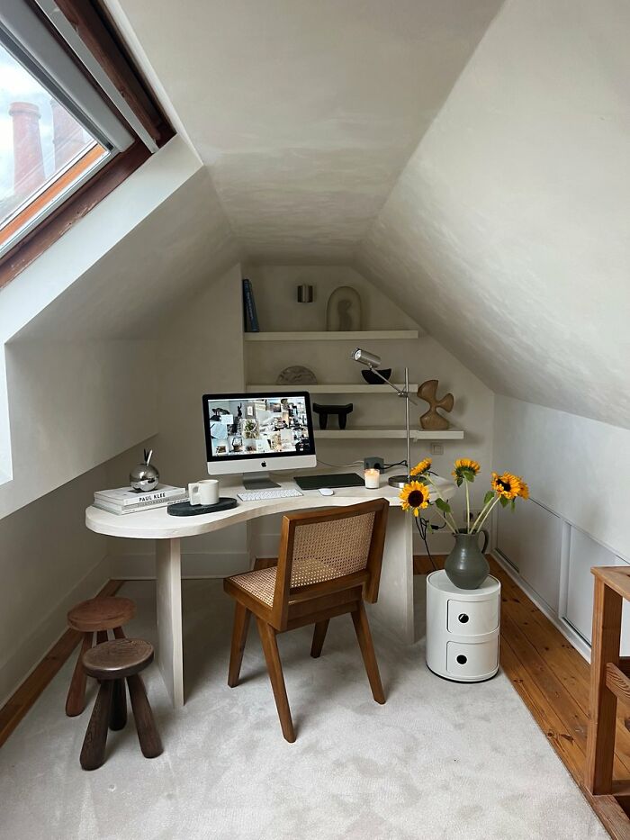 Cozy attic home office workspace with wooden chair and desk under sloped ceiling