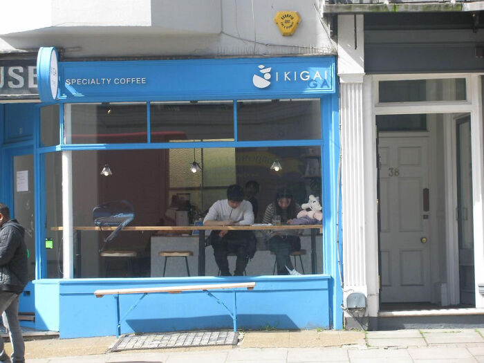 Bright blue specialty coffee shop facade with people sitting inside at wooden counter