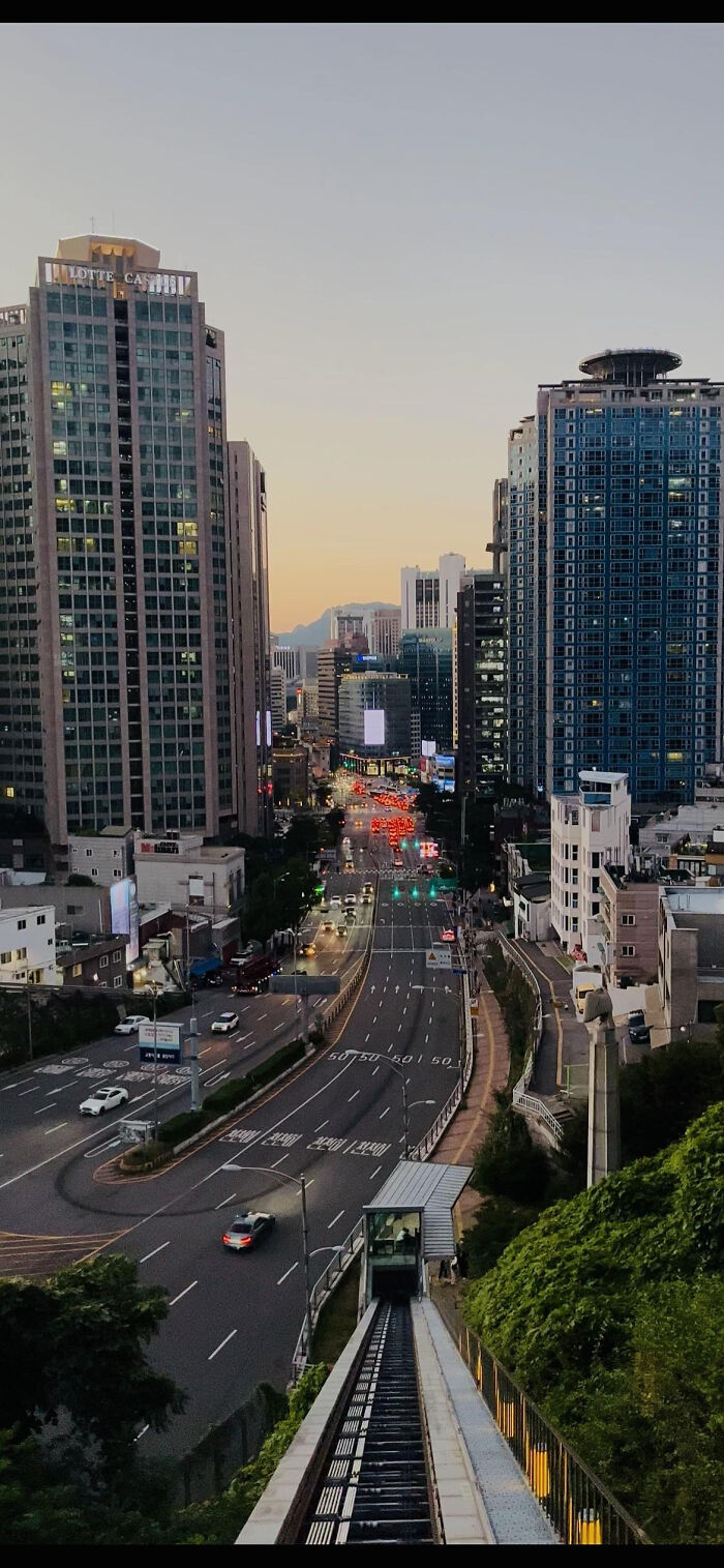 Cityscape at dusk with high-rise buildings and busy street in aesthetic photo