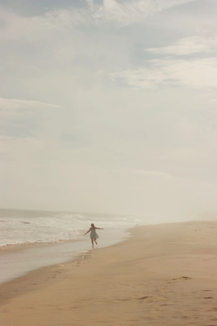 Person running along empty foggy beach in aesthetic photo
