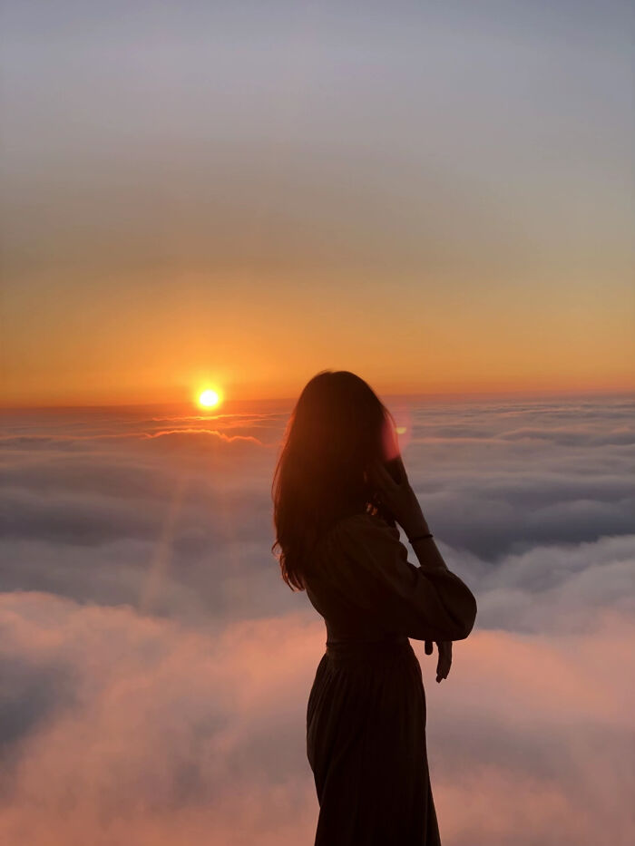Silhouette of person watching sunset above clouds in aesthetic photo