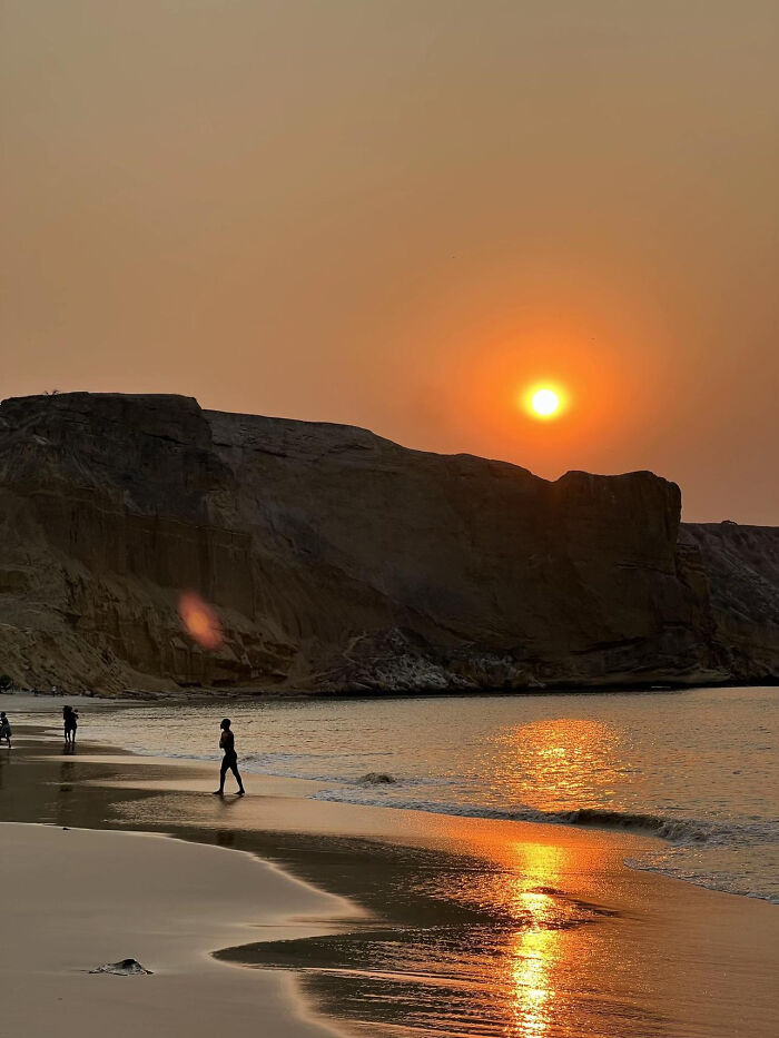 Sunset over beach with waves and cliffs in warm aesthetic golden hour light
