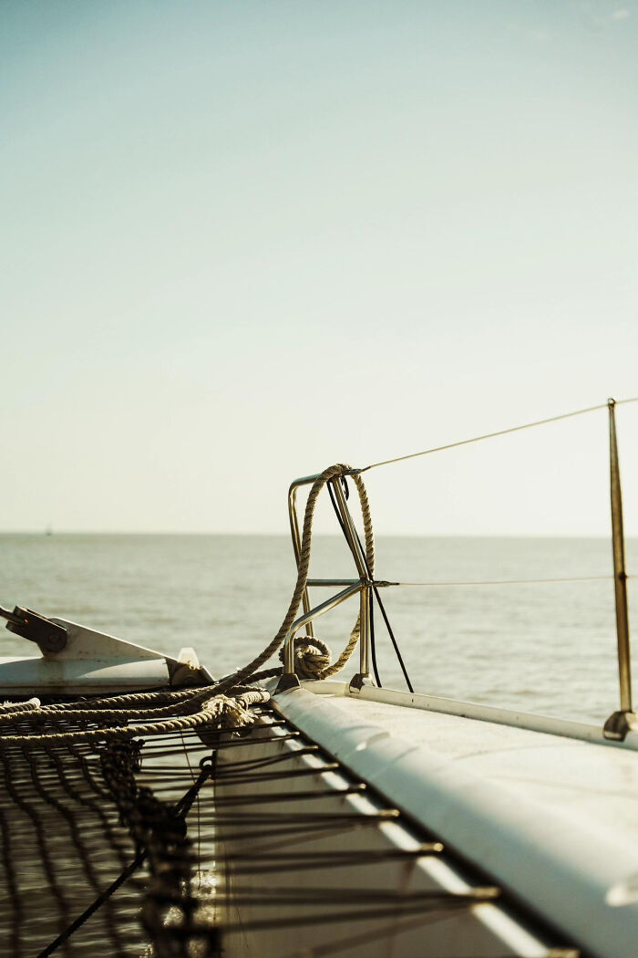 Aesthetic close-up photo of boat deck and ropes with ocean in background