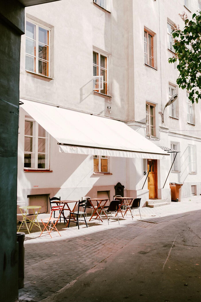 Bright outdoor cafe seating under awning on an aesthetic sunny street
