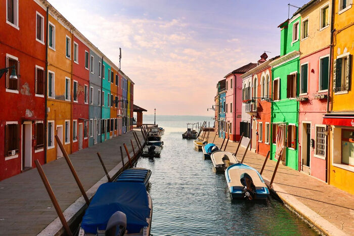 Colorful buildings lining a canal with boats at sunset aesthetic photo