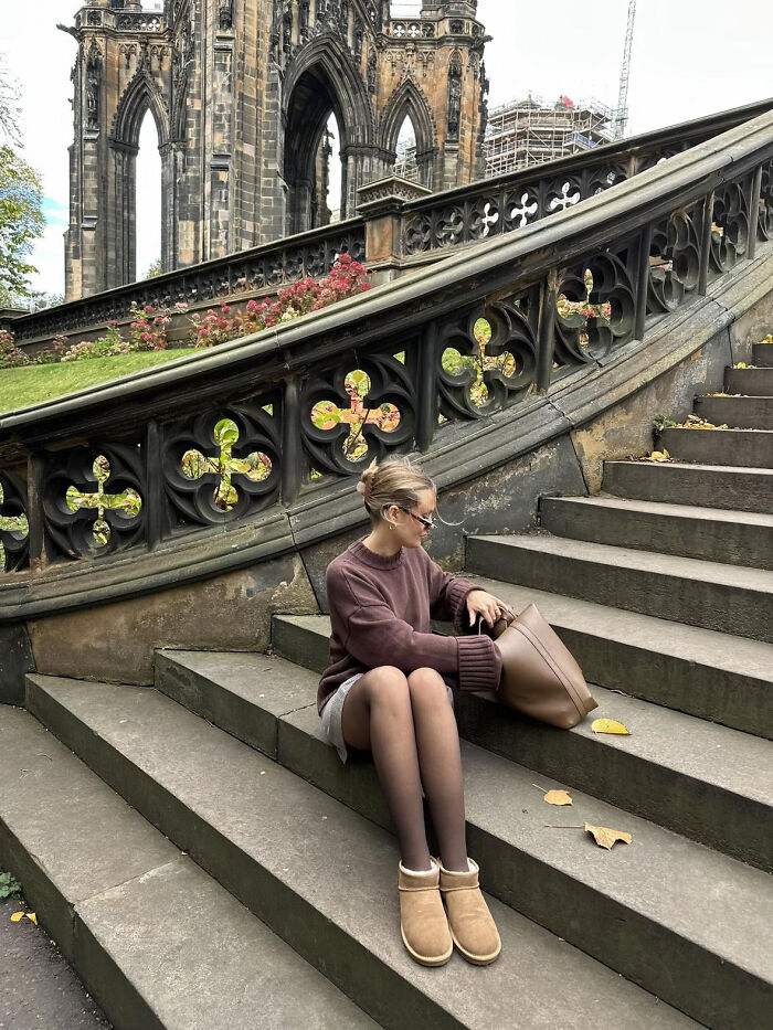 Woman sitting on historic stone steps near gothic architecture in aesthetic photo