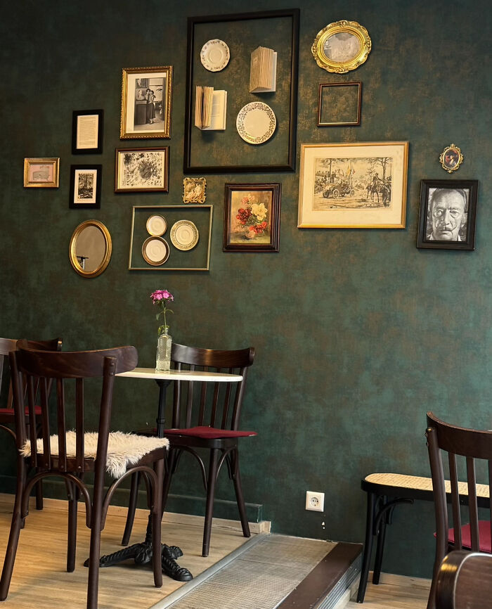 Aesthetic cozy cafe interior featuring vintage framed art and dark wooden chairs