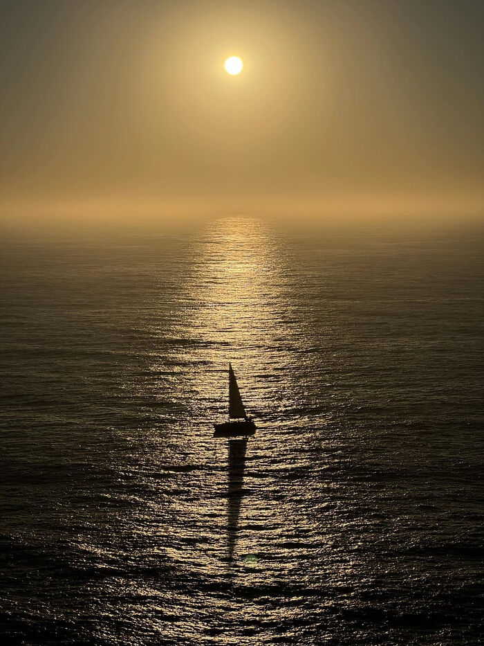 Aesthetic sunset silhouette of a sailboat on shimmering ocean water