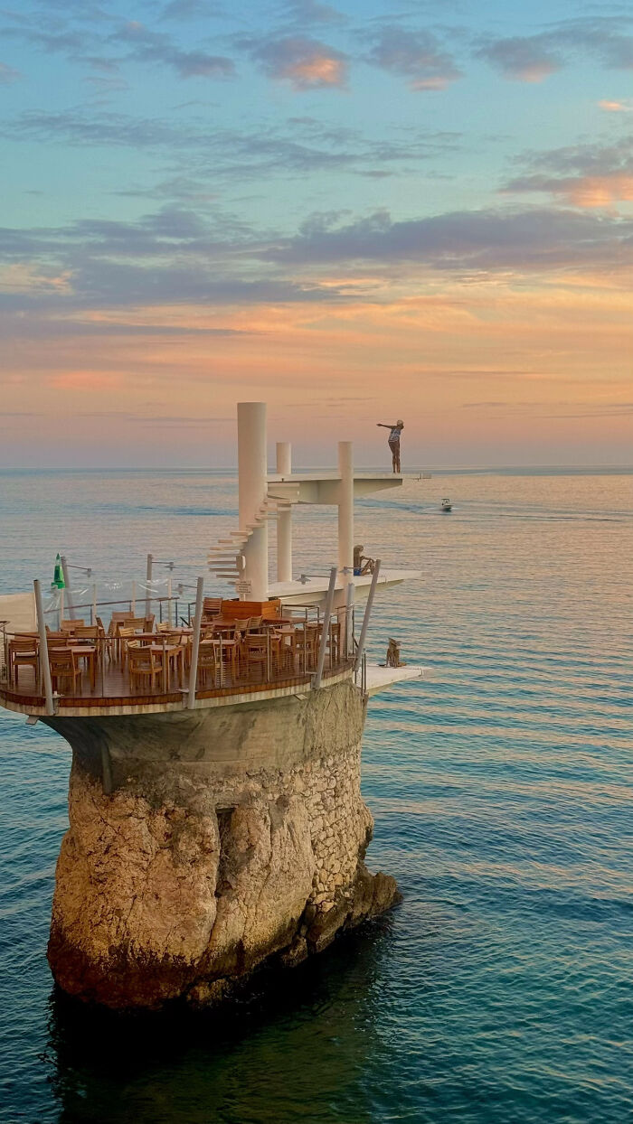 Aesthetic sunset over ocean with cliffside restaurant and diving platform