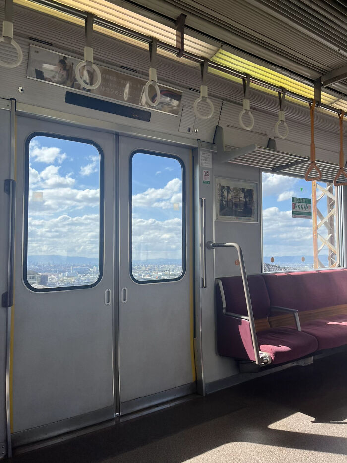 Bright daytime cityscape visible through train doors and windows